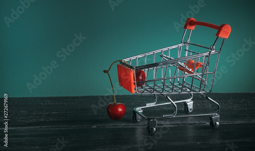 mini cart with cherries on green background
