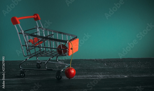 mini cart with cherries on green background