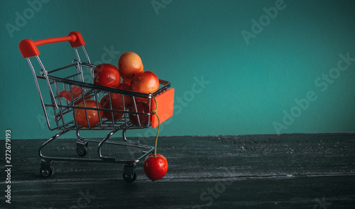 mini cart with cherries on green background