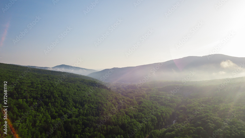 Aerial view of Caucasus mountain with haze and forest. Morning fog over the forest. Aerial view of Caucasus mountain with haze and forest. Morning fog over the forest.
