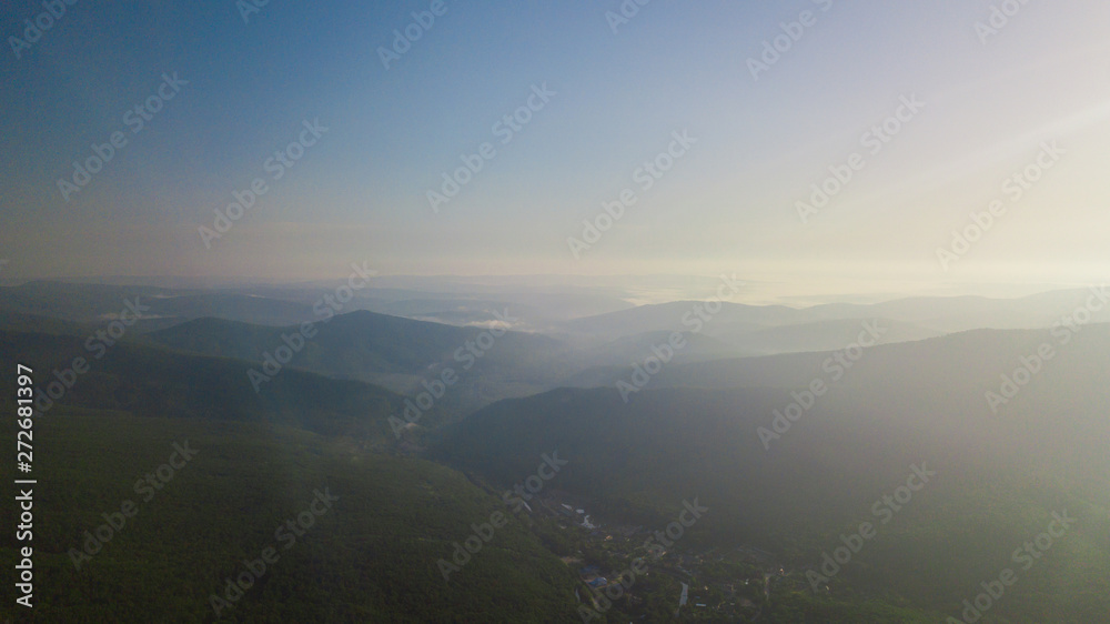 Aerial view of Caucasus mountain with haze and forest. Morning fog over the forest.