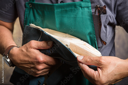 фотографія close up of orthopedic shoemaker covering a wooden last with leather