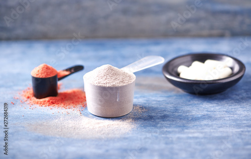 Scoop of Whey Protein, Creatine Powder and Taurine capsules. Sport nutrition. Rustic wooden background. Close up. Copy space
