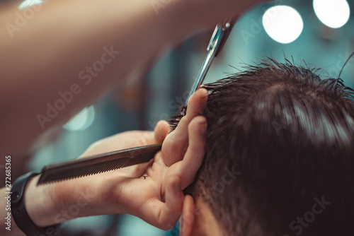 Barber makes a stylish male hairstyle.