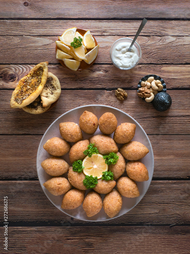 Delicious fried kibbeh with yogurt sauce in a bowl served on a plate on old wooden table. Classic Lebanese recipe