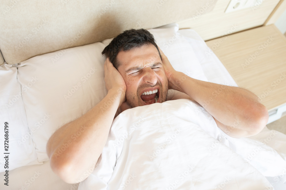 Angry man in bed awoken by a noise. Angry man in bed awoken by a noise.