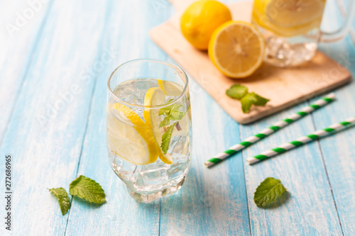 Fresh lemonade with lemon in glass on wooden background