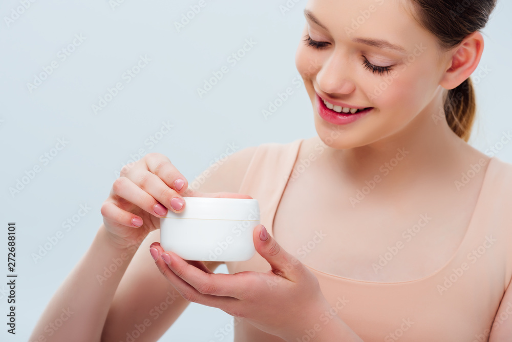 happy teenage girl holding cosmetic cream isolated on grey