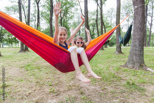 Adorable little girls relaxing on hammock in forest