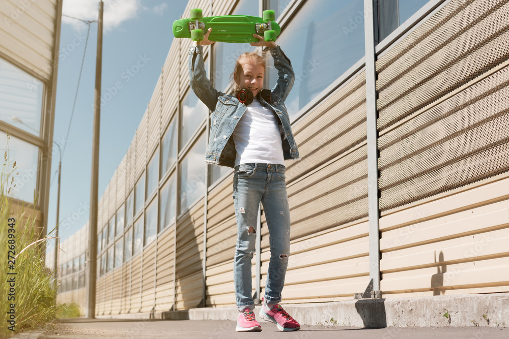 Teen on skateboard in jeans clothes, on the background of industrial