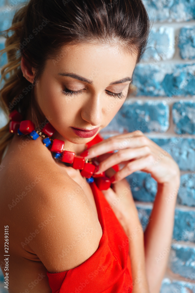 Beautiful young woman in red dress is laughing and gesturing. tudio shot on gblue background.