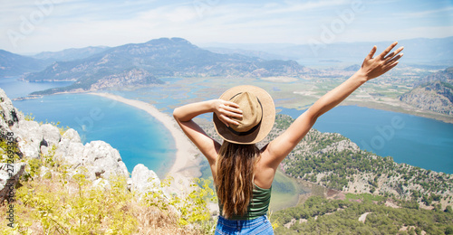 Happy woman with hands up standing on cliff over sea and islands at summer. Vintage mood, concepts of winner, freedom, happiness etc.