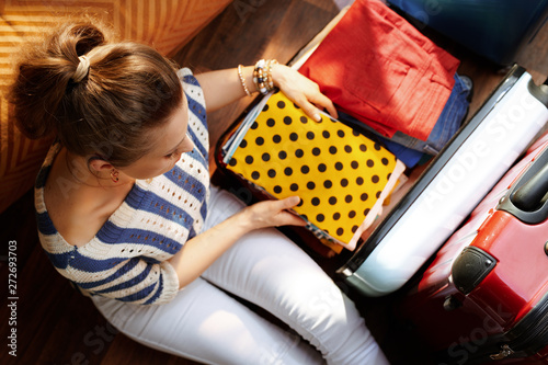 elegant woman putting stuff in open travel suitcase photo