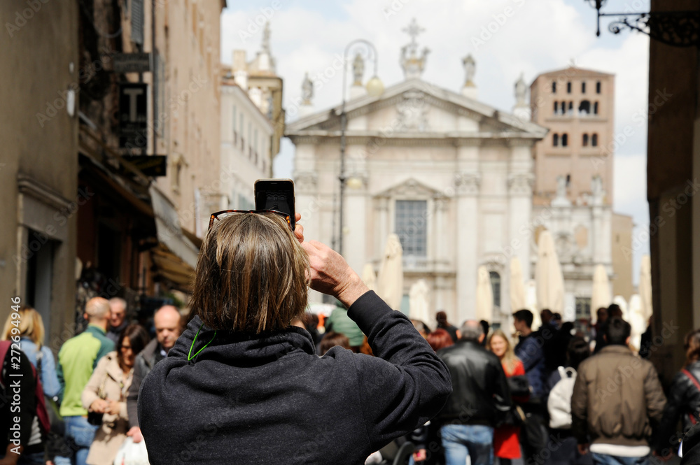 Primo piano del turista uomo sulla strada a Mantova, prendendo foto di Piazza Sordello con il telefono. Mantova, Italia