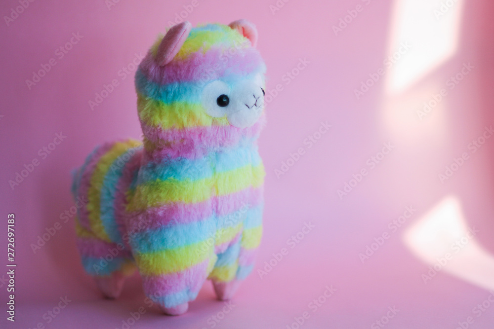 colorful rainbow Lama - soft children's toy on a pink background.