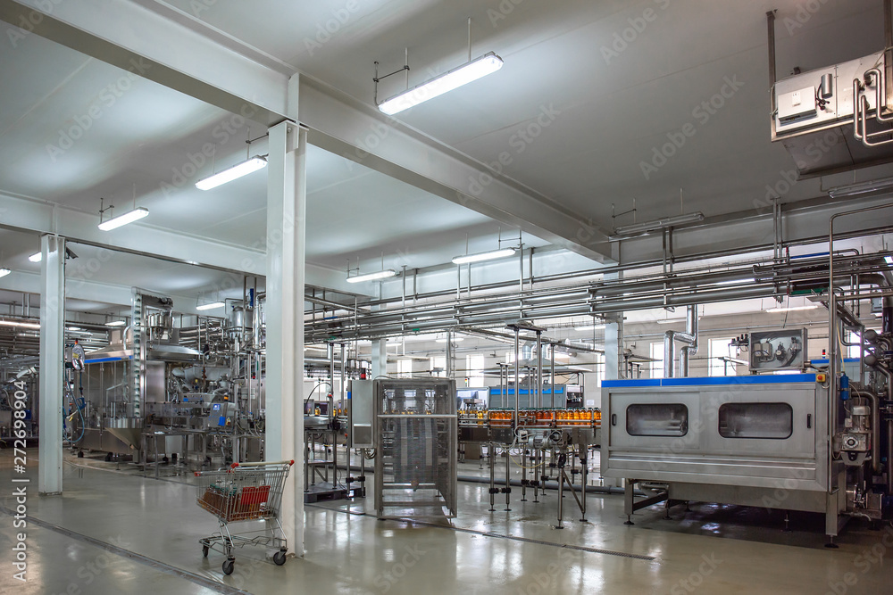 Modern beverage factory or plant interior with special industrial food production equipment. Automated conveyor belt with juice in bottles Modern beverage factory or plant interior with special industrial food production equipment. Automated conveyor belt with juice in bottles