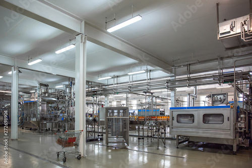 Modern beverage factory or plant interior with special industrial food production equipment. Automated conveyor belt with juice in bottles