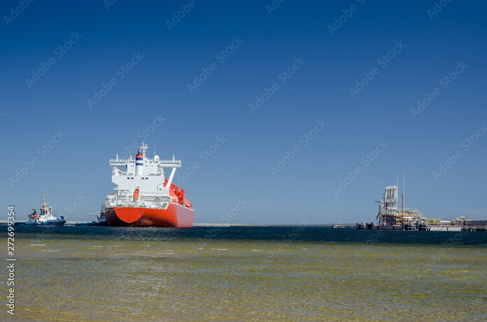 GAS TANKER AND LNG TERMINAL - The big ship maneuvers in the mooring port at the wharf