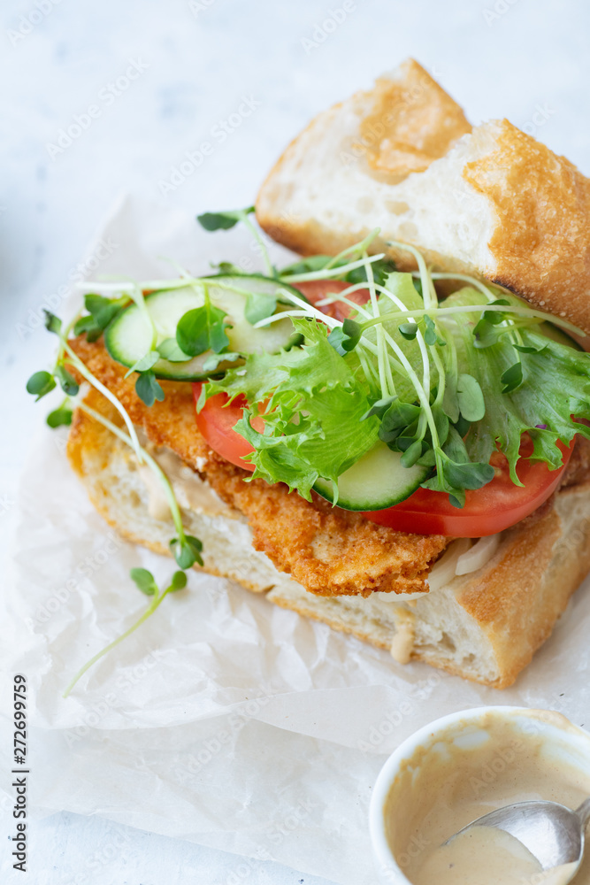 Sanwich with fried chicken on chiabatta with tomatoes, cheddar cheese, cucumber, onion, salad and microgreens Sanwich with fried chicken on chiabatta with tomatoes, cheddar cheese, cucumber, onion, salad and microgreens