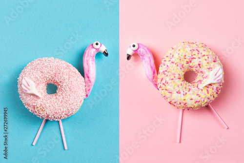 Donuts in a shape of flamingos, .on blue and pink background, top view
