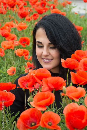 Portrait of pretty woman in field of red poppy flowers, spring time