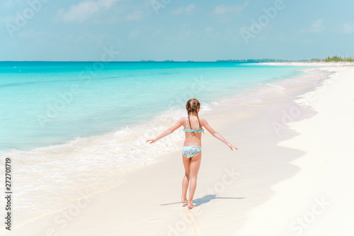 Little girl in hat walking at beach during caribbean vacation