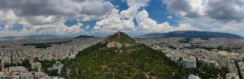 Aerial panoramic photo of famous Lycabettus hill with iconic chapel of Saint George on top and beautiful clouds,Athens, Attica, Greece