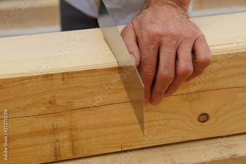 male worker hands sawing Natural Wooden beam using saw. detail, carpenter hands at work with a saw.