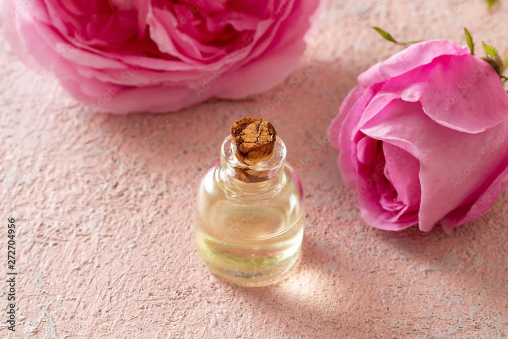 A bottle of rose essential oil with rose flowers A bottle of rose essential oil with rose flowers