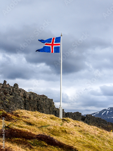 The flag of Iceland fluttering in the wind on the gloomy blue sky background.