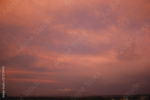 A BEAUTIFUL SUNSET SKY WITH ORANGE AND YELLOW CLOUDS WITH BLUE SKY WITH A MOUNTAINS ON THE BOTTOM OF THE PICTURE
