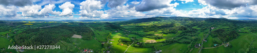Aerial wide panoramic view on sudety mountains with touristic city in the valley surrounded by meadows  forest and rapeseed fields.