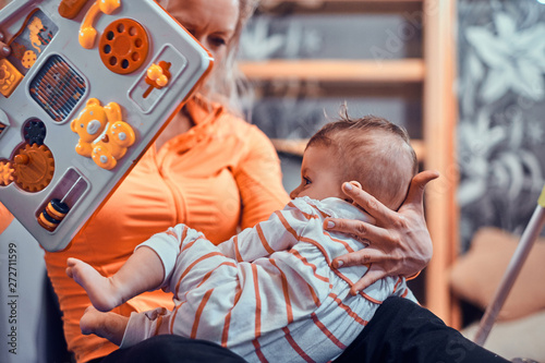 Joyful happy mom is playing with her newborn baby while waiting for a doctor at pedeatrician cabinet. photo