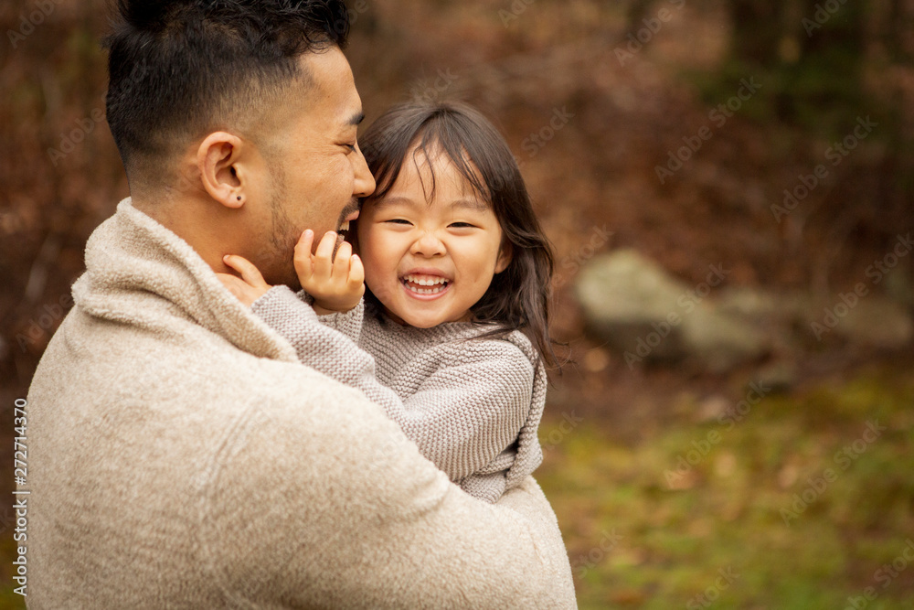 Fototapeta premium Happy father carrying cute daughter while standing in forest