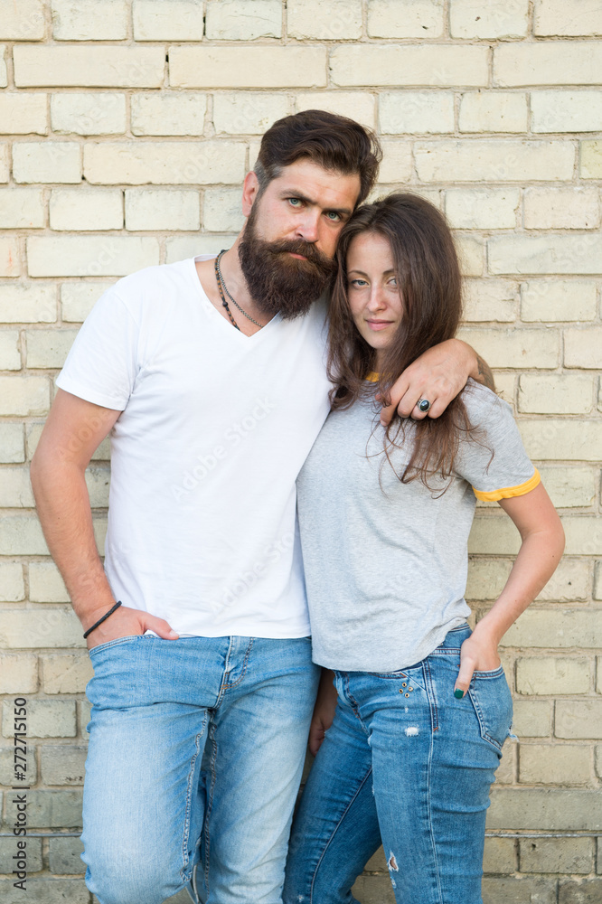 Casual couple in love. Couple enjoy each other romantic date. Man bearded and girl hug. Couple in love romantic date cuddling outdoors light brick wall background. True friendship and support