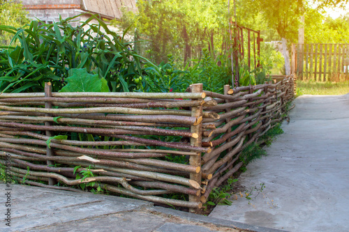 Wood wicker fence from curved wooden twigs. Wooden fence. Landscape design concept