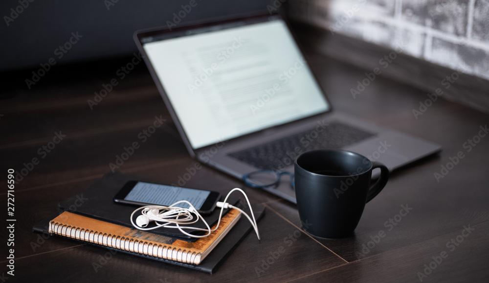 laptop and other devices on the dark floor, next to black cup of coffee laptop and other devices on the dark floor, next to black cup of coffee