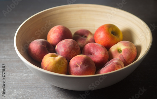 Ceramic bowl of peaches and apples on a gray table