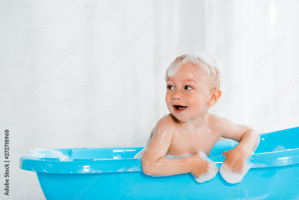 naked and cute toddler kid smiling while taking bath in plastic baby bathtub naked and cute toddler kid smiling while taking bath in plastic baby bathtub