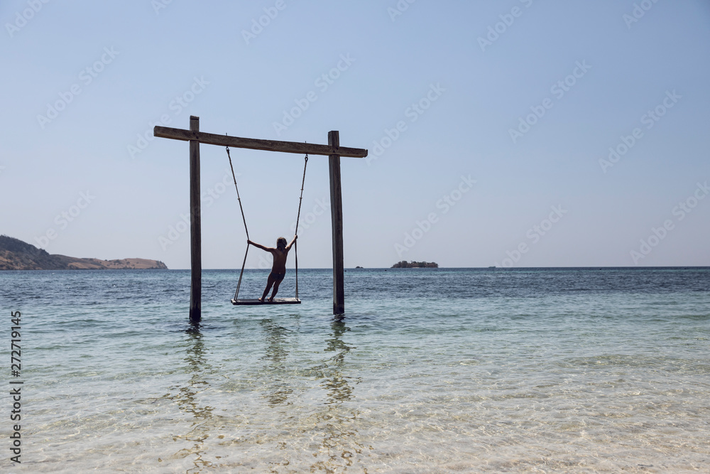 Indonesia, Komodo National Park, girl on a swing in the sea Indonesia, Komodo National Park, girl on a swing in the sea