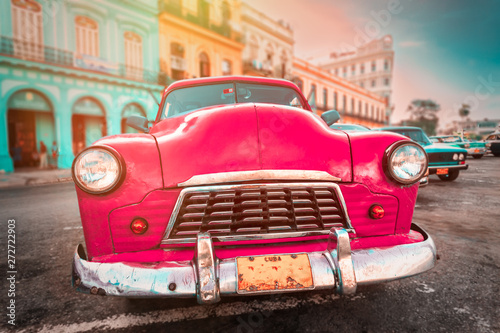 Antique pink car inext to colorful buildings in Old Havana © kmiragaya