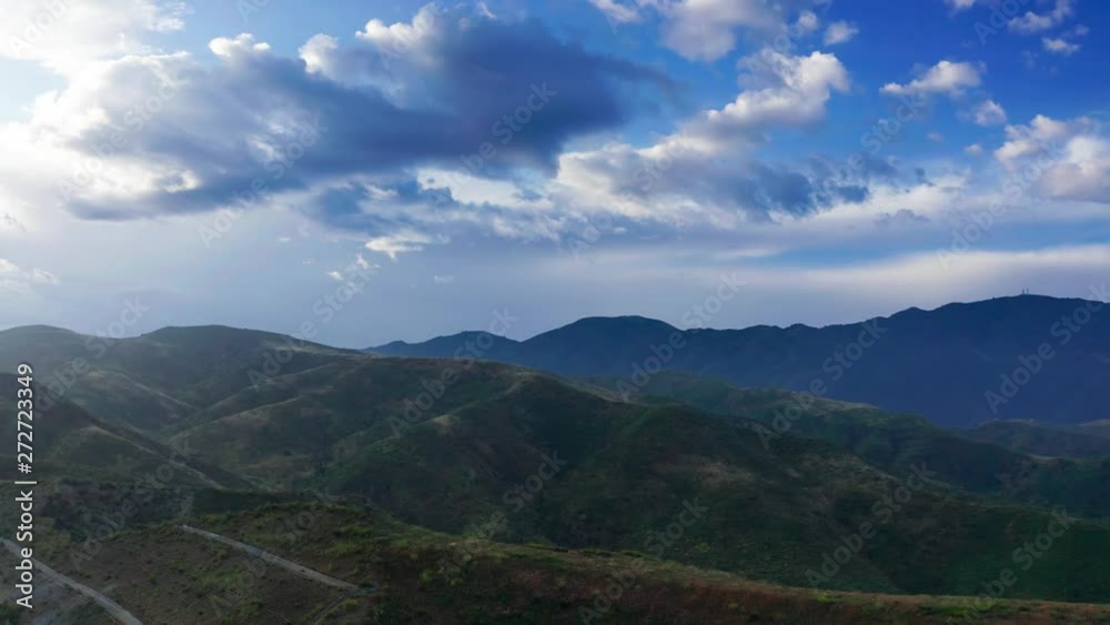 Aerial, Green mountains under cloudy blue sky with bright sunshine Aerial, Green mountains under cloudy blue sky with bright sunshine
