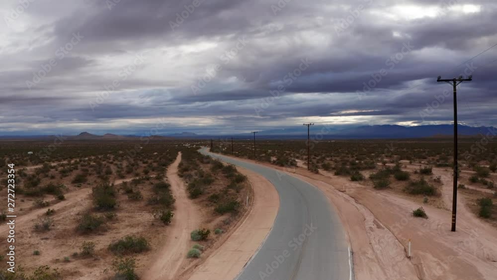 Dark storm clouds over road in vast Mojave Desert, Aerial Rising Shot Dark storm clouds over road in vast Mojave Desert, Aerial Rising Shot