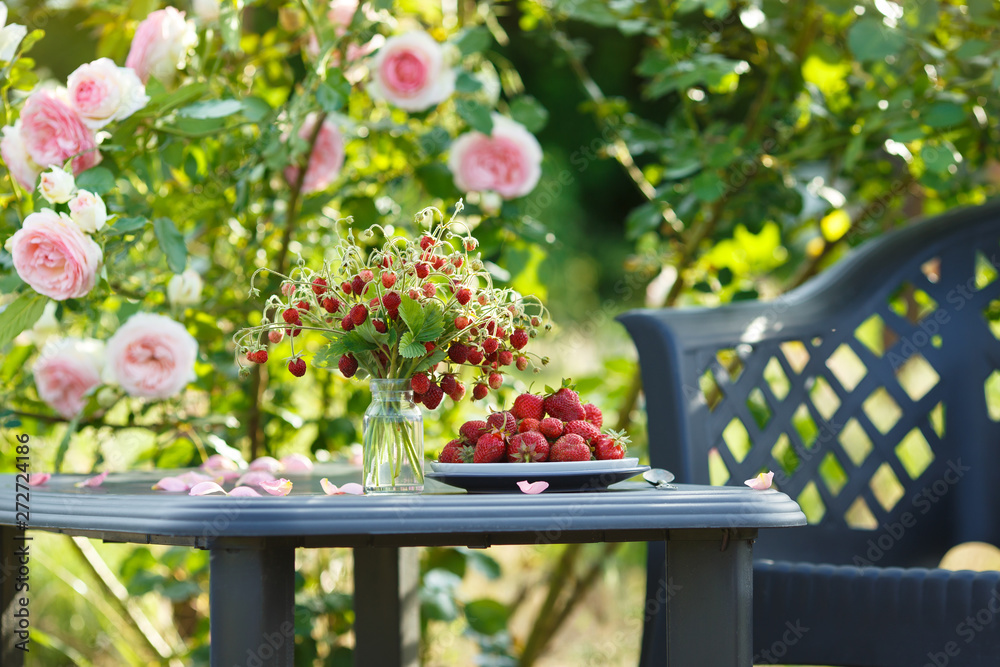 Φωτογραφία A beautiful garden with blooming roses, tasty wild strawberries and a chair