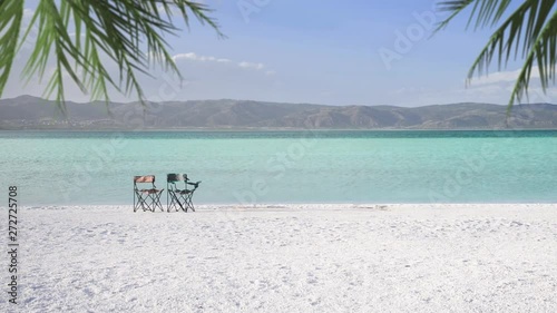 Salda lake which is like Maldives with white sand and turquoise colored water with two empty chairs and palm leaves on the scene. Burdur / Turkey. photo