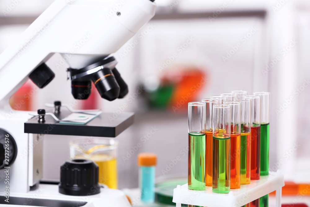 Test tubes with samples and microscope in chemistry laboratory Test tubes with samples and microscope in chemistry laboratory