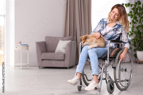 Young woman in wheelchair with puppy at home