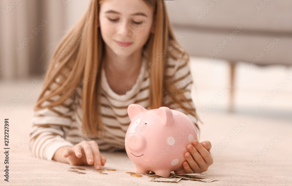 Φωτογραφία Teen girl with piggy bank and money at home
