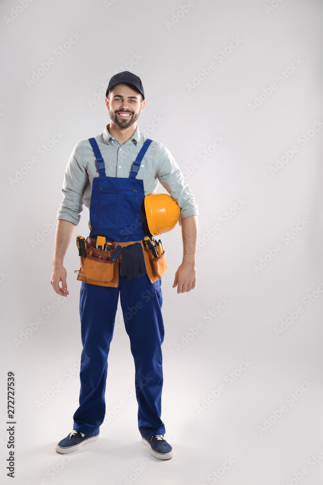 Full length portrait of construction worker with hard hat and tool belt on light background Full length portrait of construction worker with hard hat and tool belt on light background