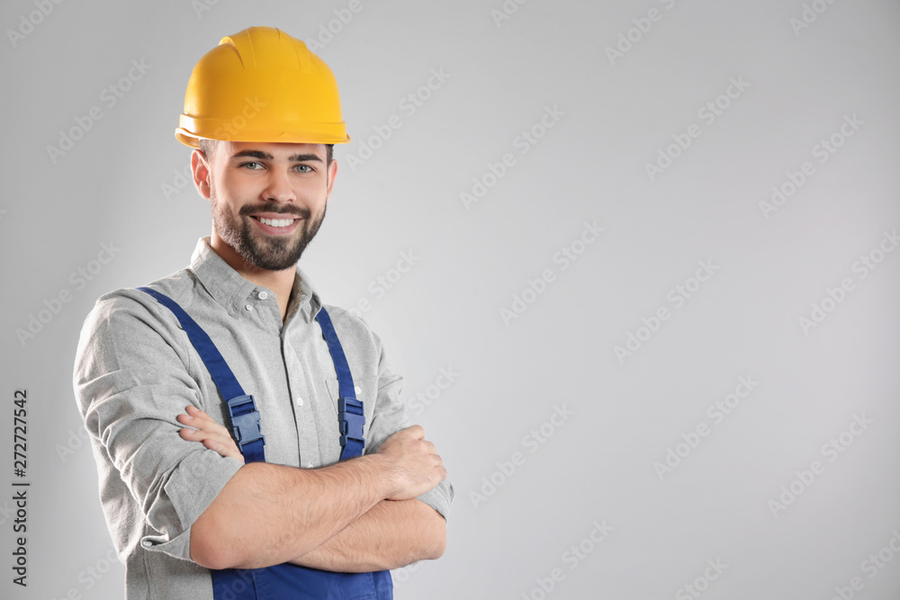 Portrait of professional construction worker in uniform on grey background, space for text